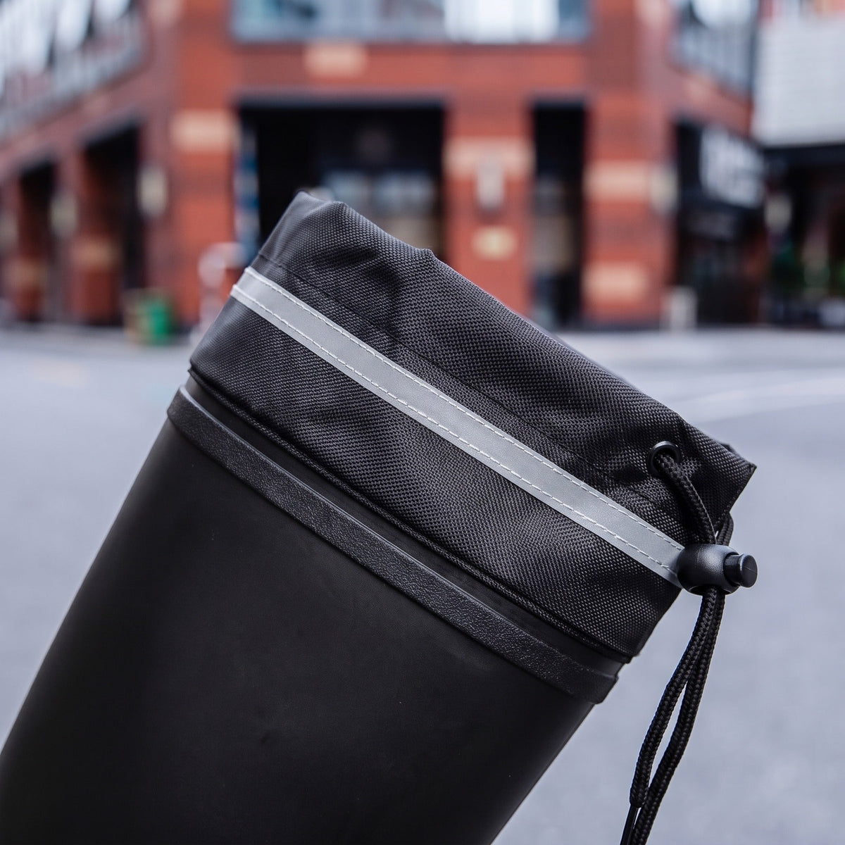 Schwarzer Gummistiefel mit Kordelzug-Tasche, getragen auf unscharfem Straßenhintergrund | Chaps Herrenmode
