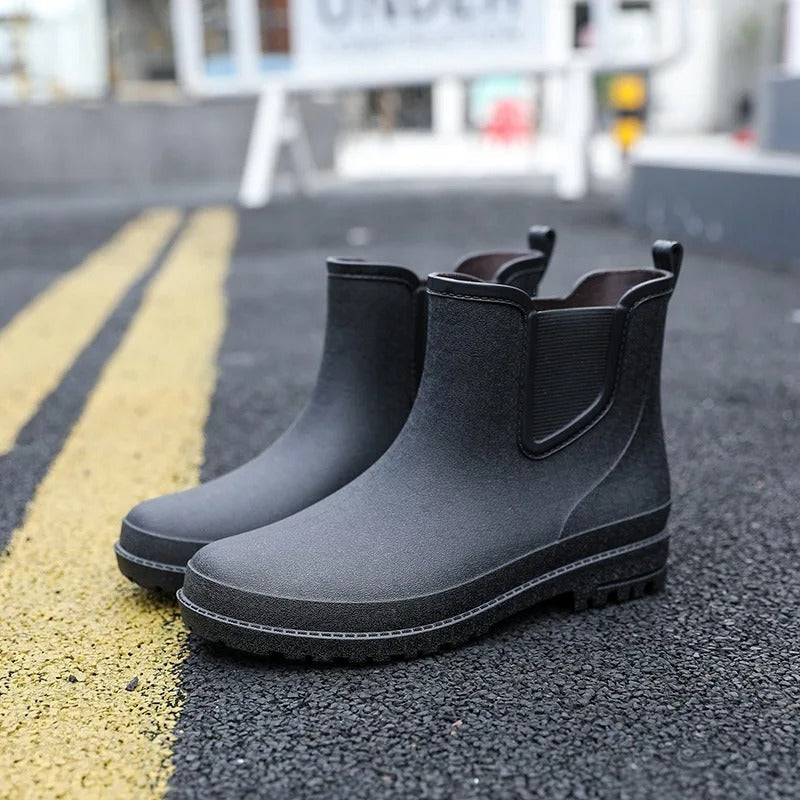 Schwarze Gummistiefel mit Chelsea-Schnitt, freistehend auf Asphalt mit gelber Markierung fotografiert | Chaps Herrenmode