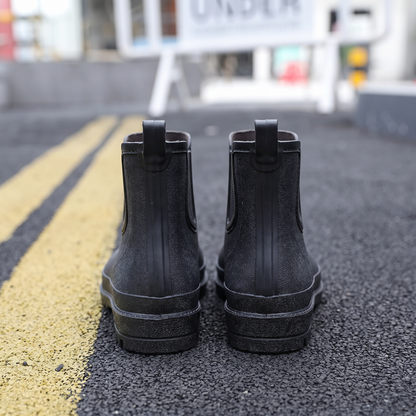 Schwarze Gummistiefel von hinten getragen auf Asphaltstraße mit Markierungen | Chaps Herrenmode