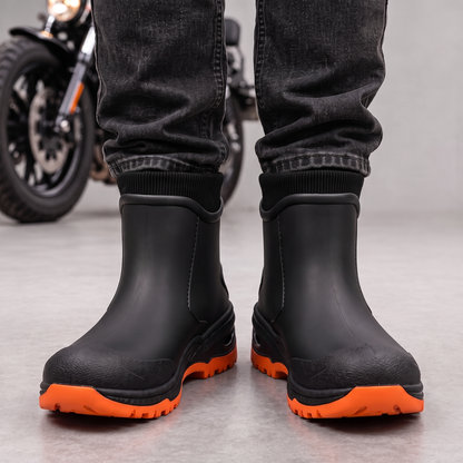 Schwarze Gummistiefel mit orangefarbener Sohle zu dunkler Jeans, Ansicht von vorne.