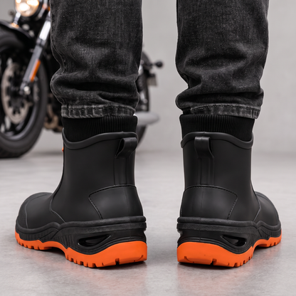 Schwarze Gummistiefel mit orangefarbener Sohle zu dunkler Jeans, Ansicht von hinten mit Anziehlaschen.