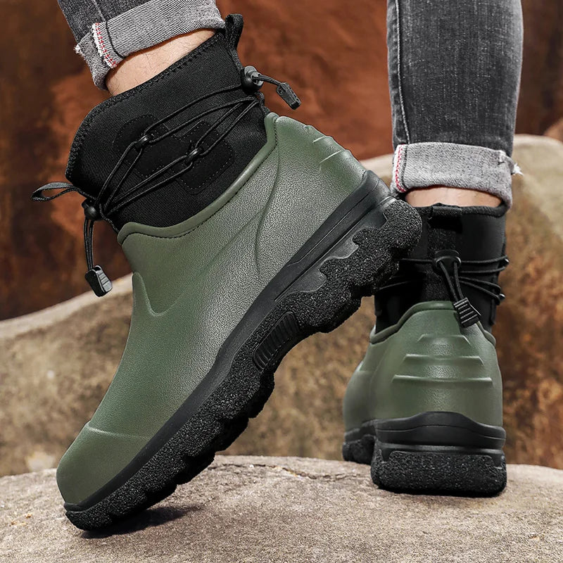 Grüner Gummistiefel mit schwarzem Schnürzug, getragen an Modellbeinen auf Felsen | Chaps Herrenmode