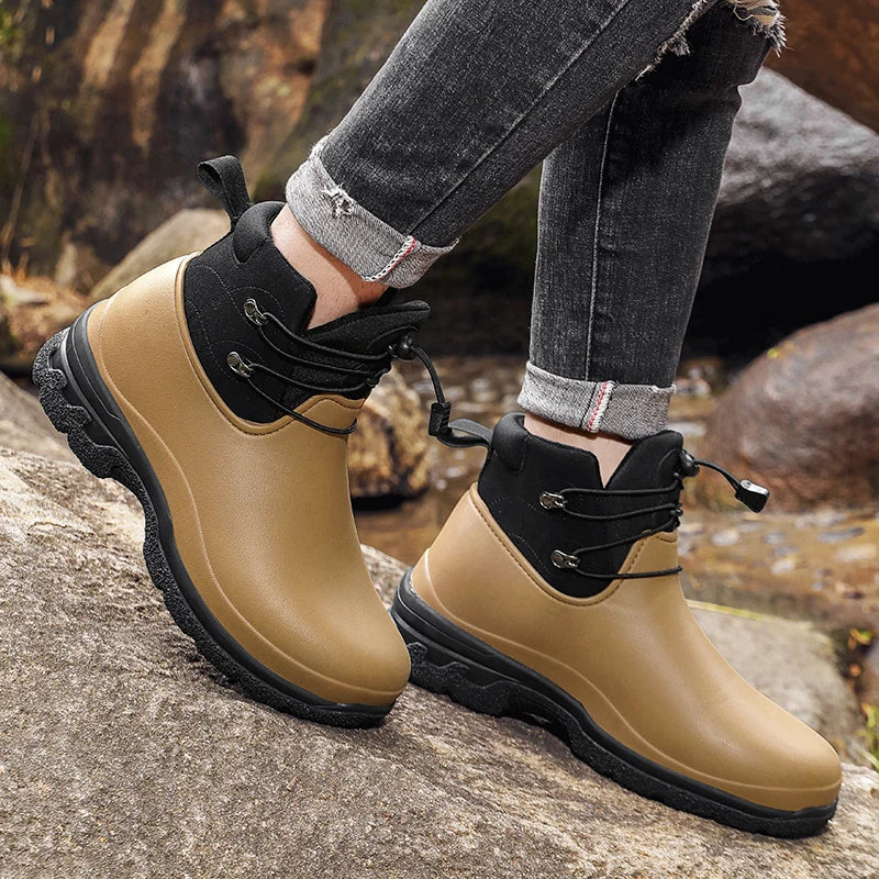 Beige-schwarze Gummistiefel mit Schnürzug, getragen an Beinen auf Felsen | Chaps Herrenmode