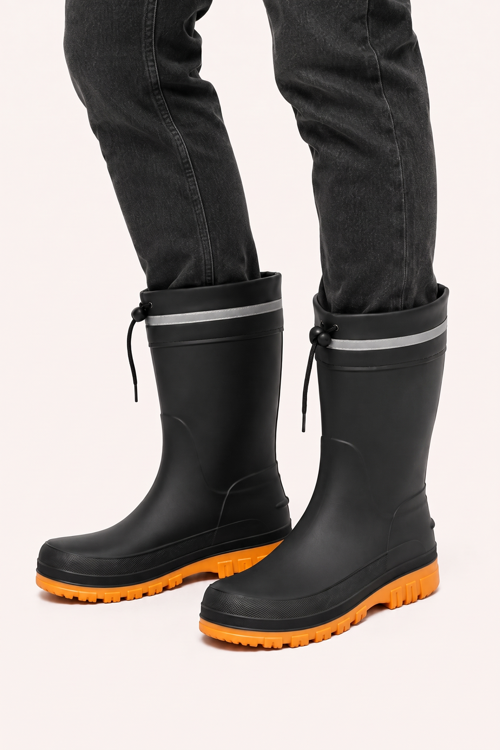 Schwarze Gummistiefel mit orangefarbener Sohle, getragen von einer Person mit Jeans | Chaps Herrenmode