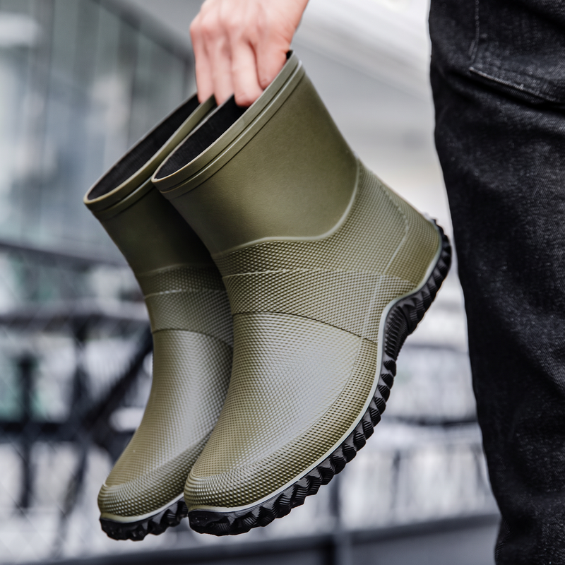 Grüne Gummistiefeletten für Herren, in der Hand gehalten