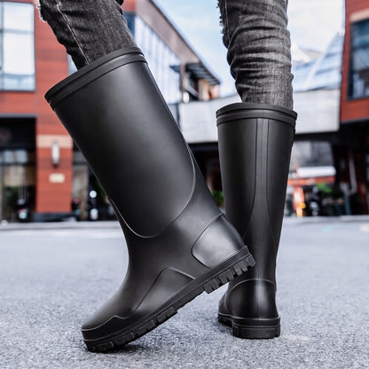 Schwarze knielange Gummistiefel mit Profilsohle, getragen von einer Person auf Straße | Chaps Herrenmode