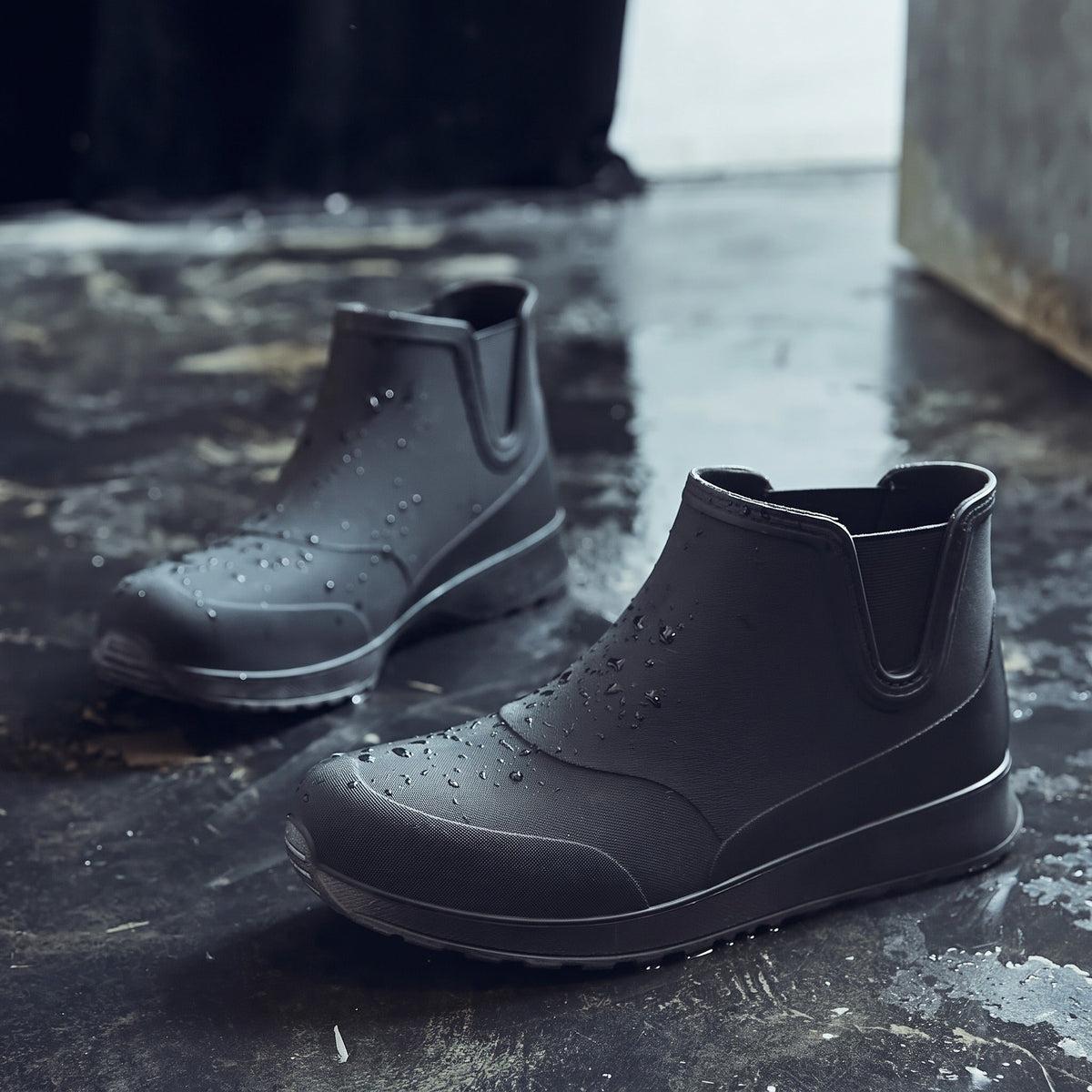 Schwarze Chelsea Regenstiefel mit kurzem Schaft, freistehend auf nasser Fläche | Chaps Herrenmode