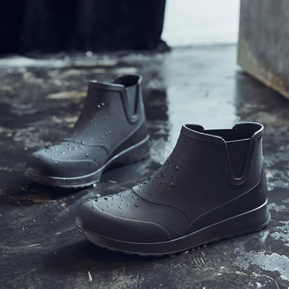 Schwarze Chelsea Regenstiefel mit kurzem Schaft, freistehend auf nasser Fläche | Chaps Herrenmode