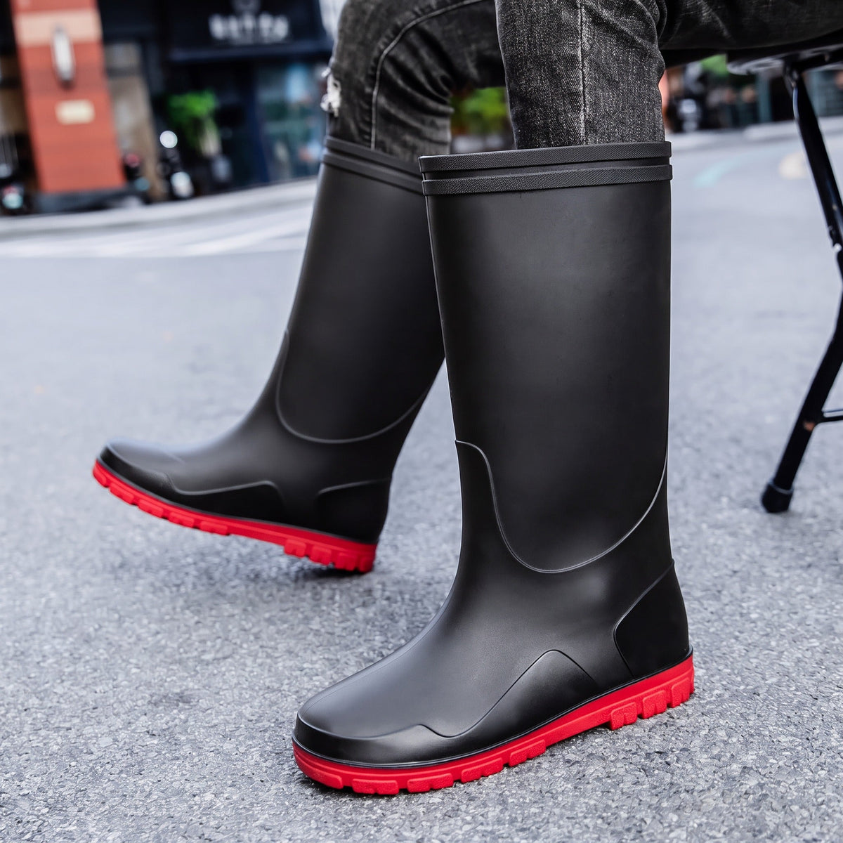Schwarze kniehohe Gummistiefel mit roter Sohle, von Person getragen | Chaps Herrenmode