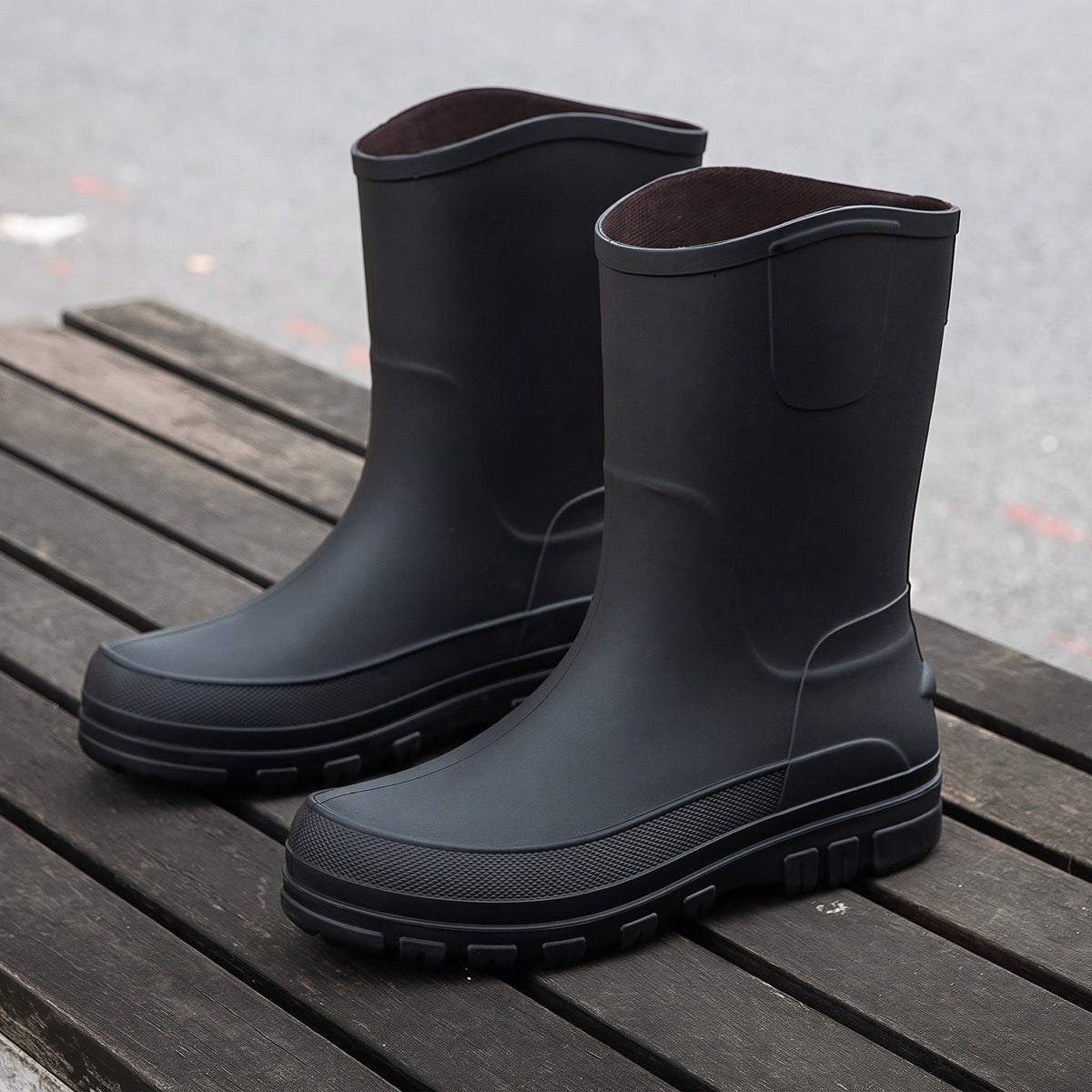 Schwarze halbhohe Gummistiefel mit Profilsohle, freistehend auf Holzterrasse fotografiert | Chaps Herrenmode