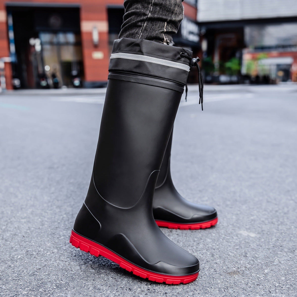 Schwarzer kniehoher Gummistiefel mit roter Sohle, von Person am Bein getragen | Chaps Herrenmode