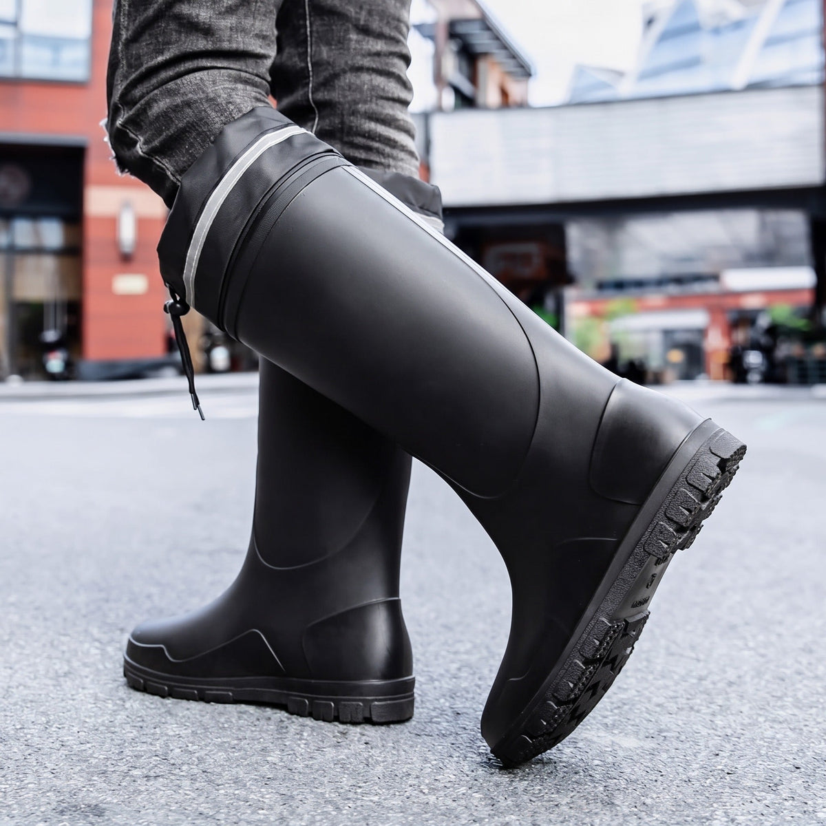 Schwarze kniehohe Gummistiefel mit Profilsohle, getragen von einer Person auf Straße | Chaps Herrenmode