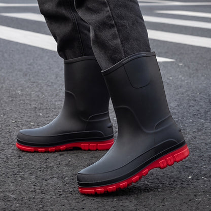 Schwarze Gummistiefel mit roter Sohle, getragen von einer Person auf Straße | Chaps Herrenmode