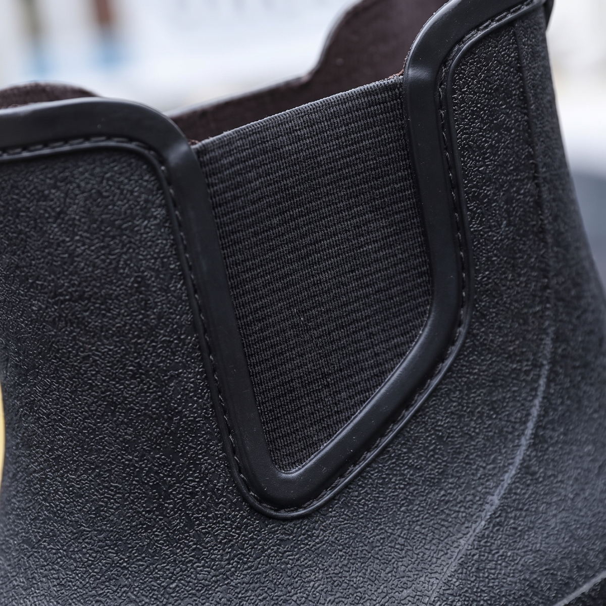 Nahaufnahme des elastischen Seiteneinsatzes am schwarzen Gummistiefel