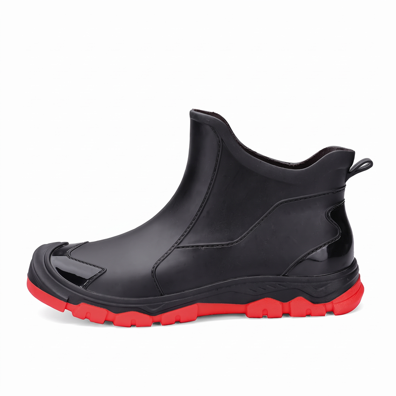 A black ankle rain boot with a red sole and a small rectangular logo patch near the top.