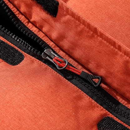 Nahaufnahme Reißverschluss mit rotem Anhänger an orangefarbener Steppjacke | Chaps Herrenmode