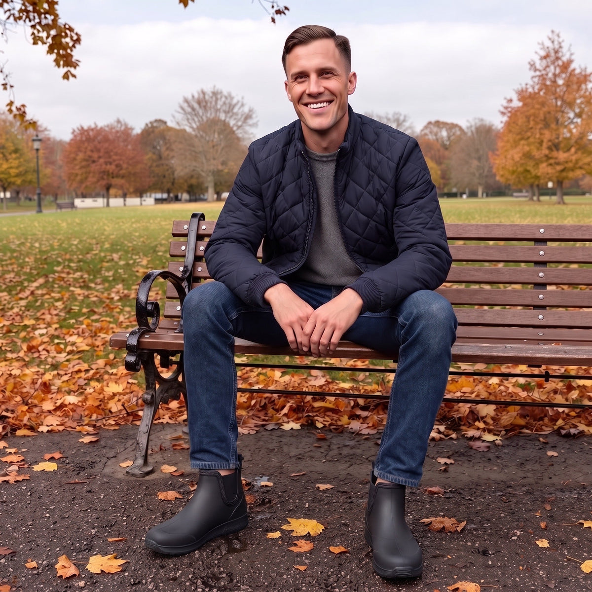 Mann trägt schwarze Chelsea-Boots mit Jeans auf einer Parkbank sitzend | Chaps Herrenmode