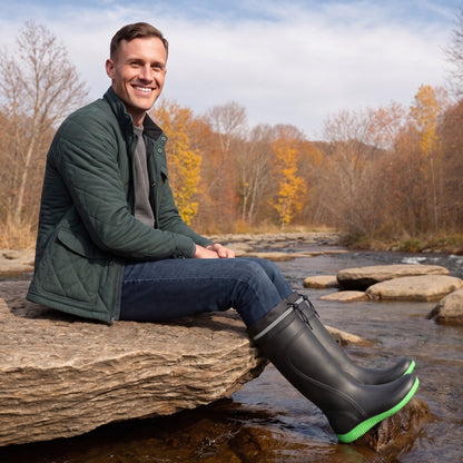 Mann trägt schwarze Gummistiefel mit grüner Sohle am Flussufer | Chaps Herrenmode