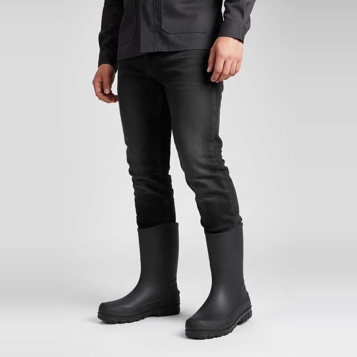 Schwarze halbhohe Gummistiefel, getragen von Person in schwarzer Jeans, Seitenansicht | Chaps Herrenmode