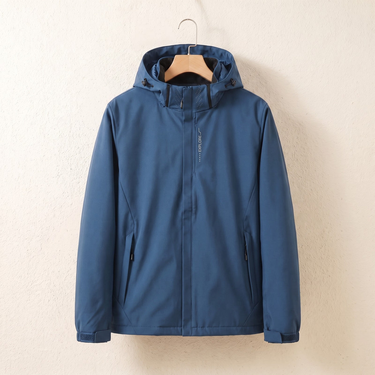 Blaue wasserdichte Jacke mit Kapuze auf dem Bügel