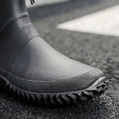 Schwarzer Gummistiefel mit Profilsohle, getragen, Nahaufnahme auf Asphalt | Chaps Herrenmode