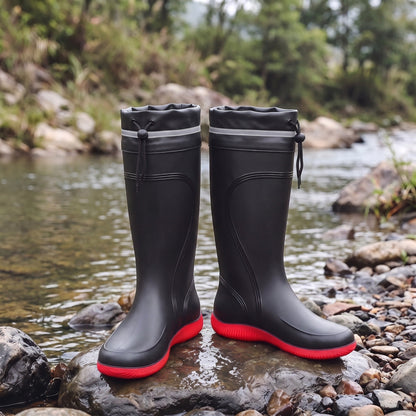 Schwarze Gummistiefel mit roter Sohle, kniehoch, auf Steinen am Fluss | Chaps Herrenmode