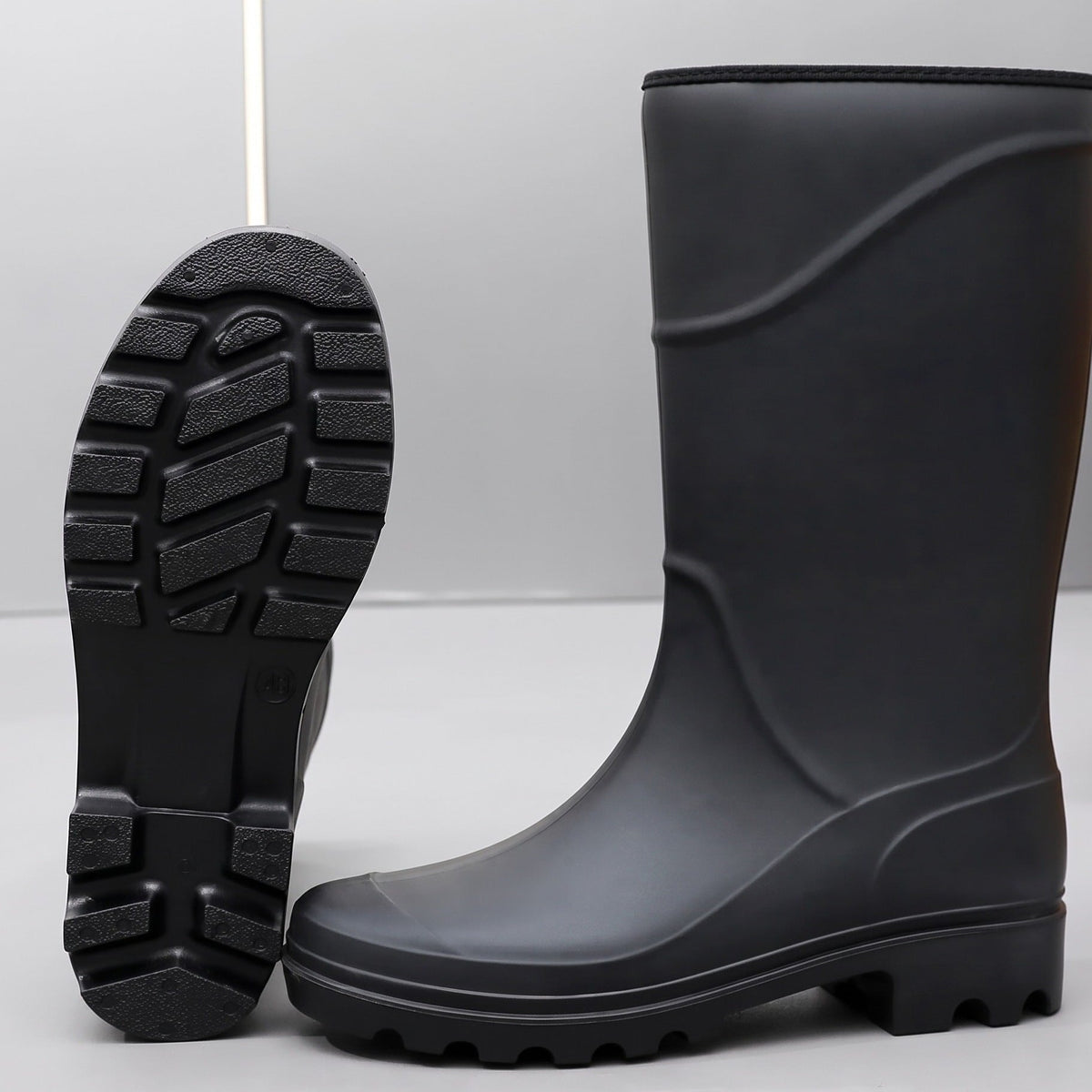 Schwarzer Gummistiefel hoch, stehend mit sichtbarer Profilsohle und zweitem Stiefel daneben | Chaps Herrenmode