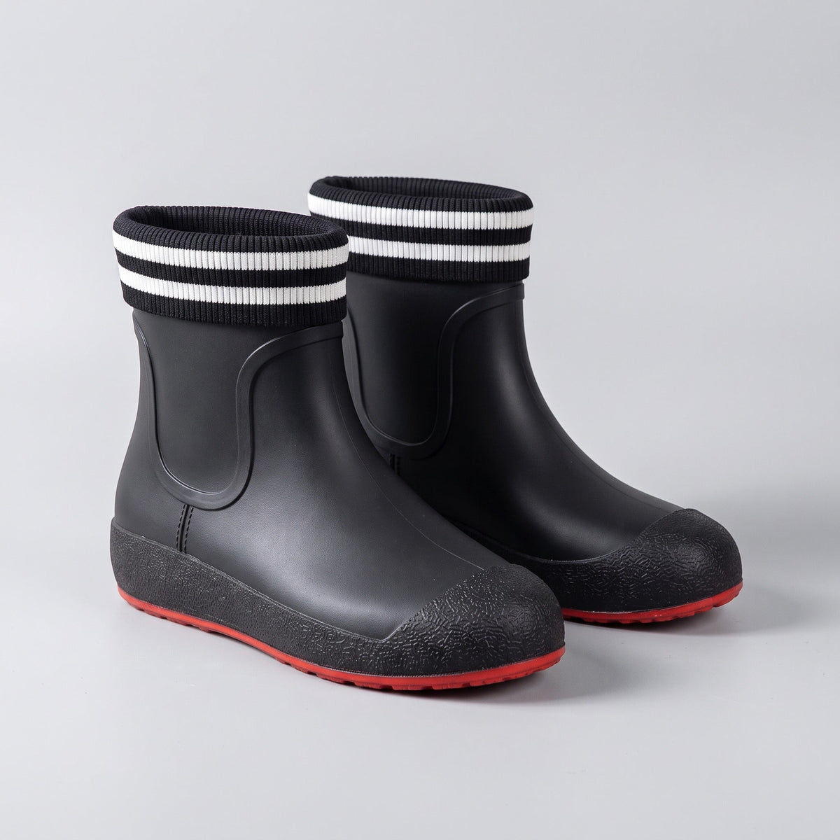Schwarze kurze Gummistiefel mit gestreiftem Bund und roter Sohle, freigestellt | Chaps Herrenmode