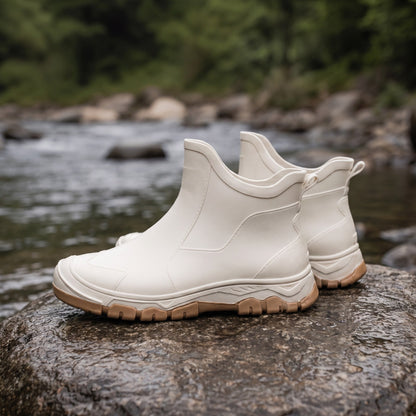 Cremefarbene kurze Regenstiefel mit Profilsohle, freistehend auf Felsen am Fluss | Chaps Herrenmode
